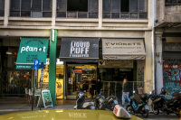 a taxi is passing a street with stores and motorcycles in monastiraki in athens