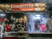 a man in a clowd of smoke ist turning suflaki skewers in kremasti on rhodes