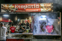 a man in a clowd of smoke ist turning suflaki skewers in kremasti on rhodes