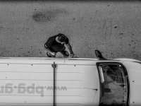 from above you see a driver in chalkida, how he is getting in his white van, black-and-white