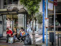 three woman are sitting and talking together at a bus stop in athens