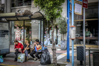 three woman are sitting and talking together at a bus stop in athens