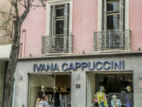 two women are passing a fashionstore of ivana cappuccini in athens