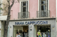 two women are passing a fashionstore of ivana cappuccini in athens
