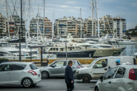 a man is walking alone against the traffic on the street next to the harbor pasalimani in piraeus