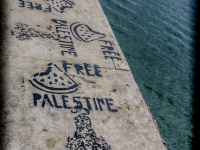 next to the blue sea in piraeus is a harbor wall where ist lettering free palestine