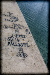 next to the blue sea in piraeus is a harbor wall where ist lettering free palestine