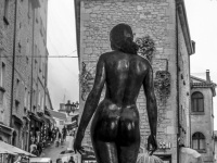 tourists in the alleys of san marino are looking at the bronze statue statua grande nudo femminile, black-and-white