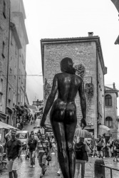 tourists in the alleys of san marino are looking at the bronze statue statua grande nudo femminile, black-and-white