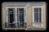 a young man is sitting on balkon of the appartement one three one - in the heart of athens in, which is building in the classicism