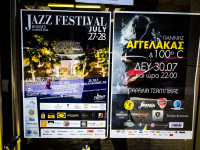 two posters with notice for concerts are hanging behind a glass door in aegio in greece