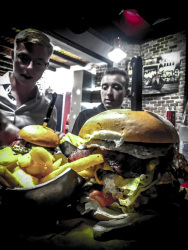 in the restaurant memphis bbq grill in rhodes city two young man are looking behind two fat burger at their food