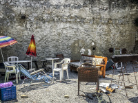 in a grey backyard in lardos on rhodes are standing various chairs, tables, couches, umbrellas and a grill