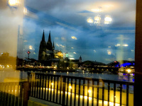 through a window of the restaurant whith name oasis with many lights you see the dom of cologne with a evening blue sky