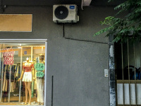 a wall in archanglos on rhodes with a store window with clothes, an air conditioner, an old door and at tree