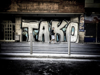 on a street in athens a man is passing a big graffiti at a wall