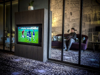 at the lounge of the hotel XII apostel in cologne a young man is watching football on tv