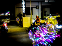 a woman on a motorcycle is watching colorful and bright lights next to her on the street in kremasti on rhodes