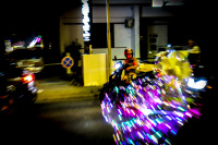 a woman on a motorcycle is watching colorful and bright lights next to her on the street in kremasti on rhodes
