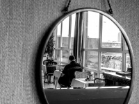 in a mirror you see a man sitting at breakfast in the hotel esprit in bratislava, black-and-white
