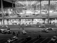 view from the hotel steigenberger at the airport in berlin to the airport with many taxis by night, black-and-white