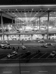 view from the hotel steigenberger at the airport in berlin to the airport with many taxis by night, black-and-white