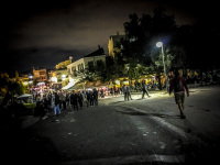 a street scene by night with many people and lights on a street in thiseio in athens