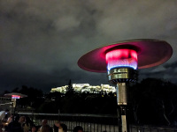 behind a colorful patio heater you see the illuminated acropolis of athens by night