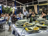 in the tavern limnioni in stegna on rhodes there are many guests behind a stack of plates