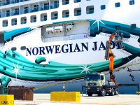 a truck with crane seems very small in front of a cruise ship norwegian jade in the harbor of rhodes
