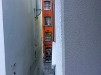 through two white housewalls you see a little part of an orange house in the salzgasse in cologne
