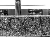 behind a wall full of padlocks at the hohenzollernbrücke in cologne drive past a train, black-and-white