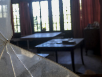 view through a damaged window in an old room with two tables in elafos on rhodes