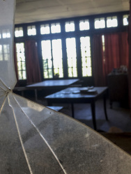 view through a damaged window in an old room with two tables in elafos on rhodes