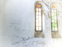 a white room with damaged colored windows and graffiti on the wall in profitis ilias on rhodes