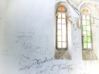a white room with damaged colored windows and graffiti on the wall in profitis ilias on rhodes