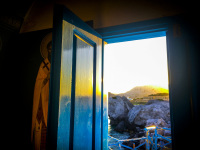 view from the dark churchroom of agios nikolaos to a hill in kolimbia on rhodes, were the sun goes down