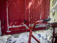 an old red bike is standig in forward to a red wooden window in the old town of rhodes