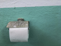 a lonely toilet paper roll is hanging on a turquoise wall in the restroom of a taverna in glyfada on rhodes