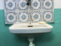 a lonely washbowl is hanging on a turquoise wall with nice tiles in blue and white in the restroom of a taverna in glyfada on rhodes
