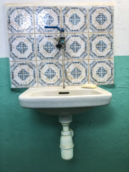 a lonely washbowl is hanging on a turquoise wall with nice tiles in blue and white in the restroom of a taverna in glyfada on rhodes