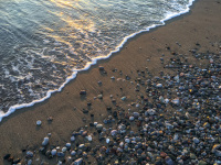 stones and a shallow wave at the limni beach by a nice sunsetlight