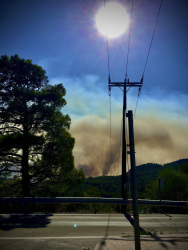 an electricity pole is standing in front of the big fire in apollona on rhodes in 2023, a big yellow clowd of smoke is in the background