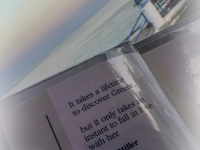 with a sunset sea in the background ist in front am menu card with a text form henry miller, who loves greece