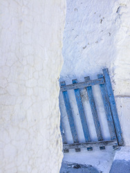 a blue wooden gate stands between white limestone walls in arnitha on rhodes