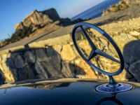 the star of a CLK mercedes benz in front of the skyline of lindos with the acropolis on rhodes