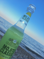 a halffull bottle of mojito classic in front of the sea in stegna on rhodes at sunset