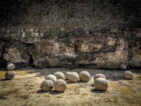 a dozen cannonballs are laying in front of the wall of the grandmaster palace in rhodos old town