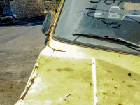 a yellow oldtimer is standing in rhodes city, in the background is the wall of the grandmaster palace