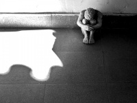 the small art statue of a men who cowers at the floor,  black-and-white and many shadows
